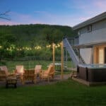 The Hog Mountain Chalet backyard at dusk with hot tub, fire pit seating and mountain views in Fleischmanns, NY